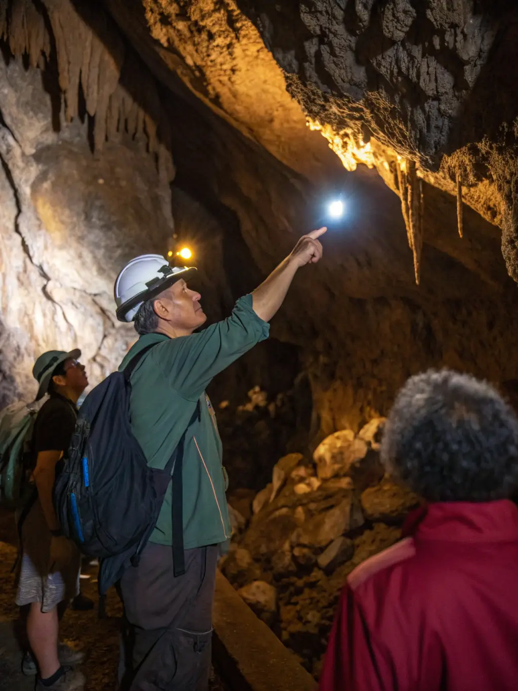 A scenic view of a guided tour group exploring a limestone cave system in the Horte et Tardoire region, led by a knowledgeable guide with a tablet showing prehistoric cave art.